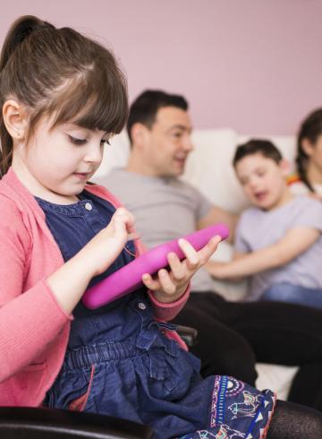 Petite fille trisomique en fauteuil roulant utilisant une tablette numérique.